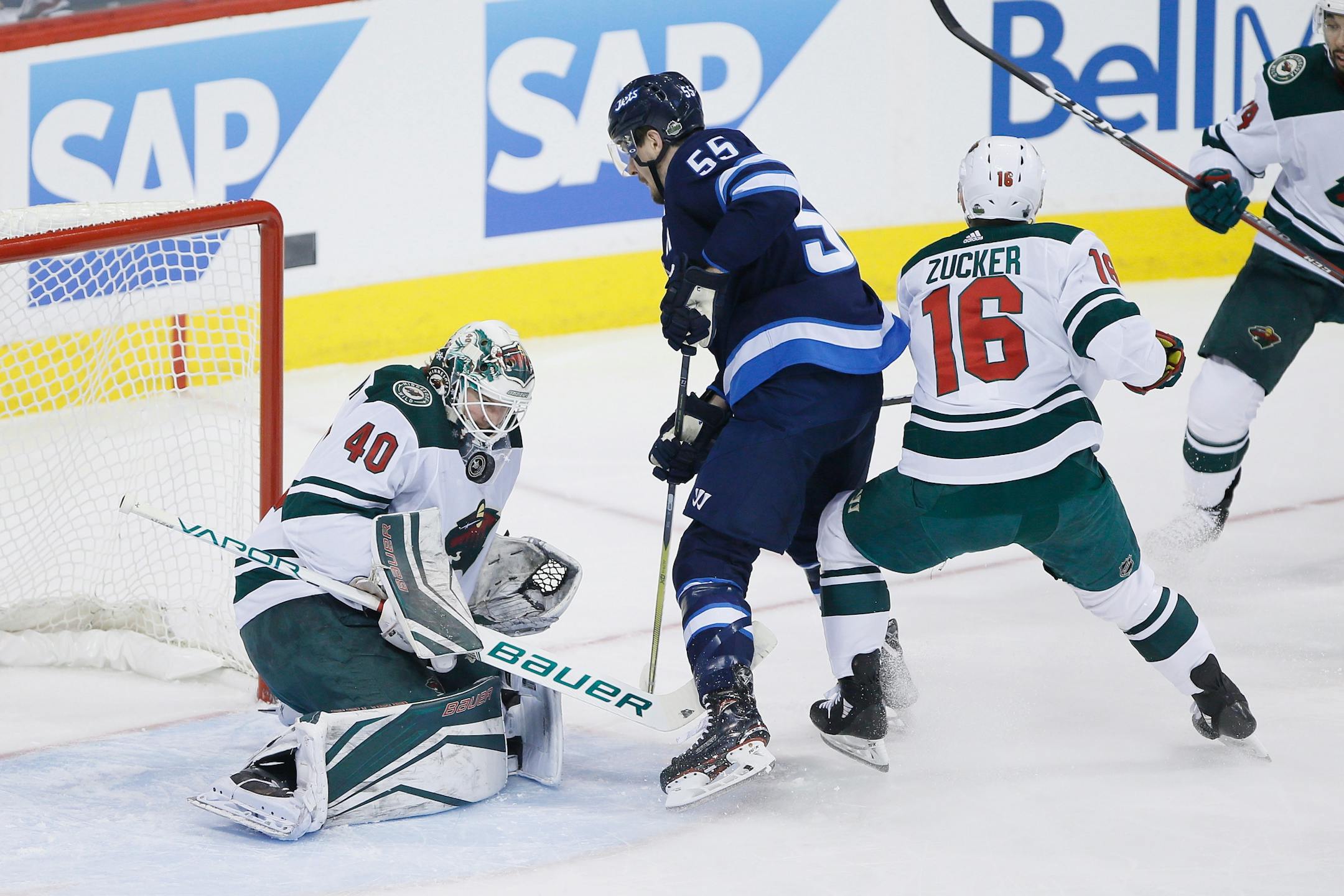 Minnesota Wild goaltender Devan Dubnyk (40) saves the shot from Winnipeg Jets' Mark Scheifele (55) as Jason Zucker (16) defends during the first period in Game 5 of an NHL hockey first-round playoff series in Winnipeg, Manitoba, Friday, April 20, 2018.