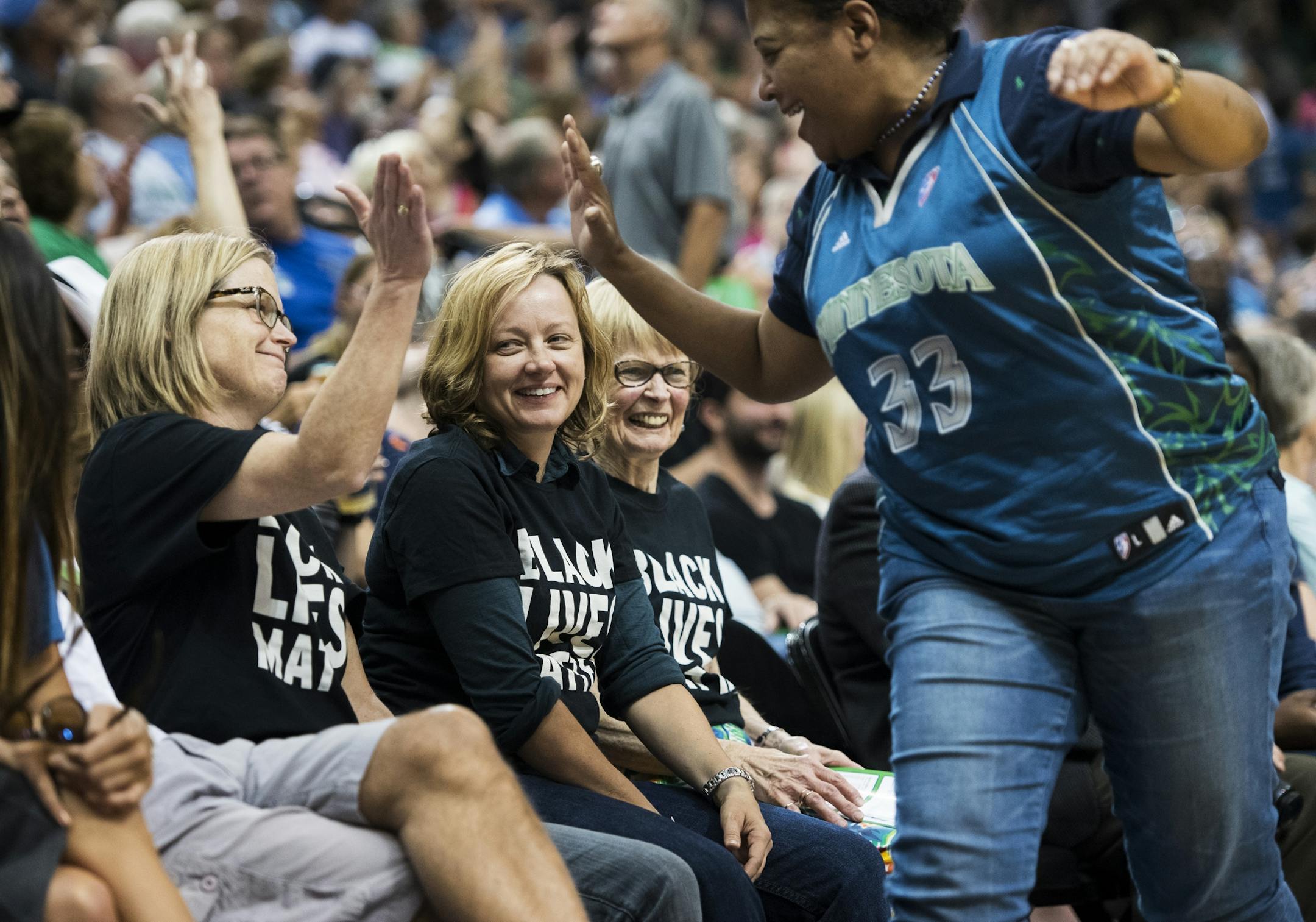 Cindy Booker, right, high-fived Vija Brookshire after high-fiving their mutual friends Julieann Swanson, center, and Jacqueline Teisberg. The three wore Black Lives Matter shirts to Friday night's Lynx game.