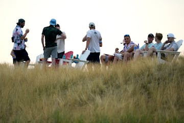 Fans sat and stood along the course after a rain delay was announced during the third round of the 3M Open.