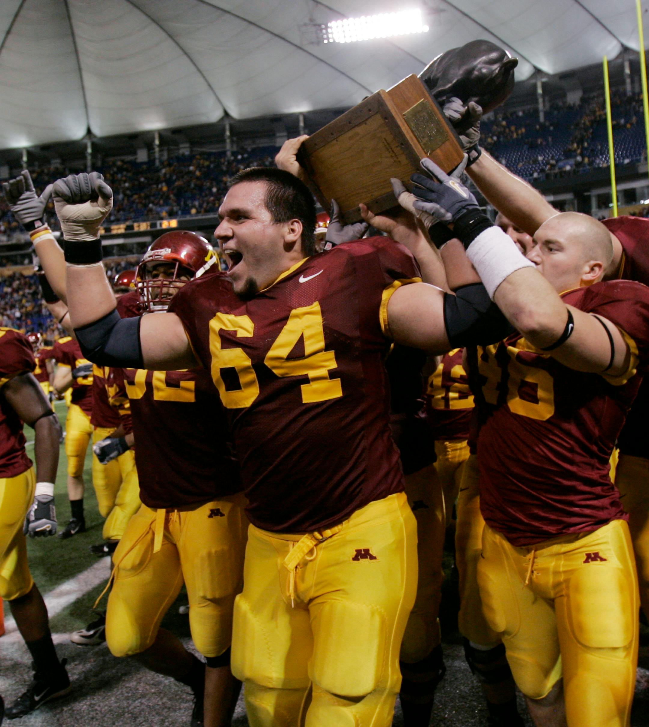 Minnesota's Steve Shidell (64) and John Shevlin, right, led the pack as they carried Floyd of Rosedale, a bronze pig, around the field after beating Iowa 34-24 in 2006.