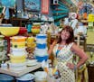 Toni Johnson with stacks of Pyrex mixing bowls and casseroles sold at her shop, Turquoise Vintage.