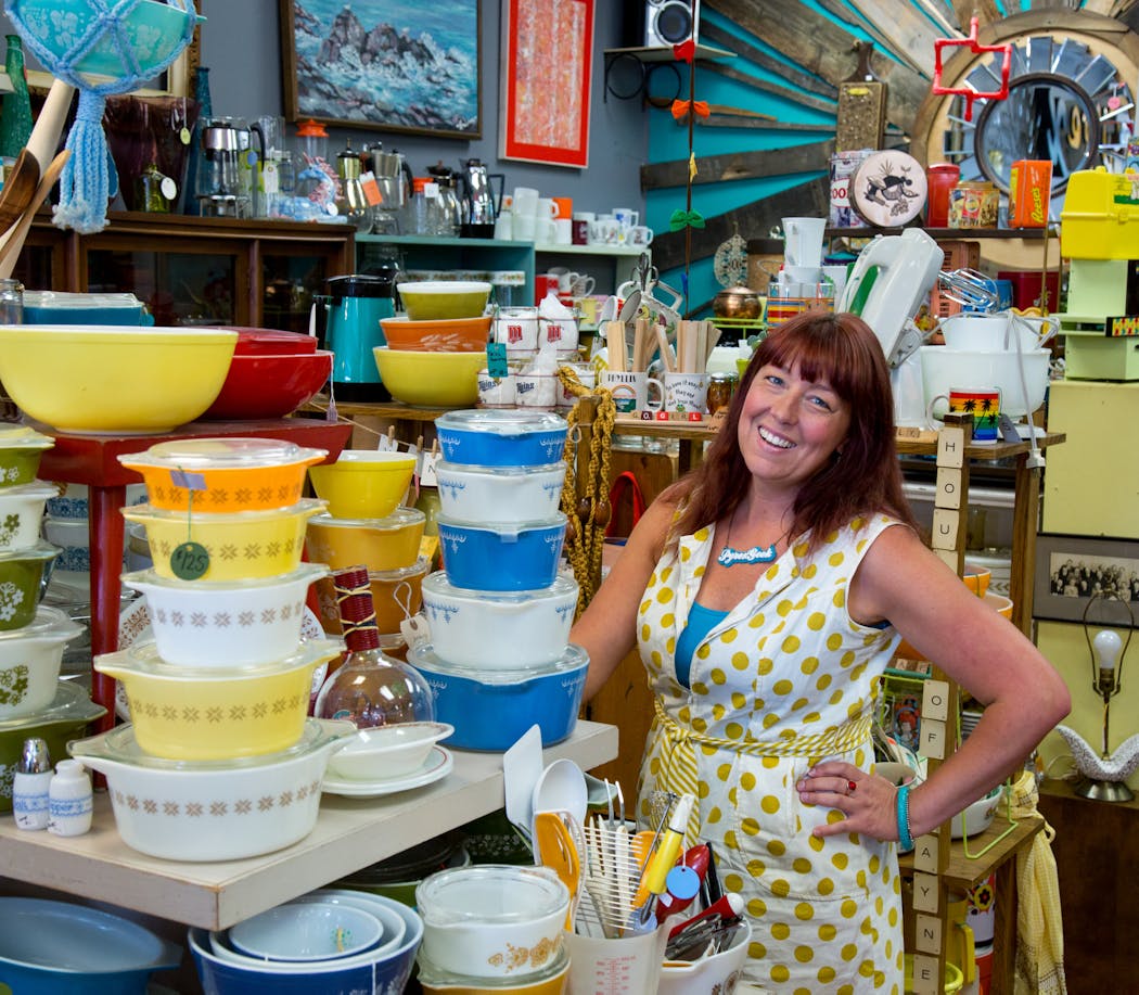 Toni Johnson with stacks of Pyrex mixing bowls and casseroles sold at her shop, Turquoise Vintage.
