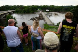 People gather to watch the Rapidan Dam on Monday, June 24, 2024 near Mankato. Water in the river significantly cut around the west side of the dam, wh