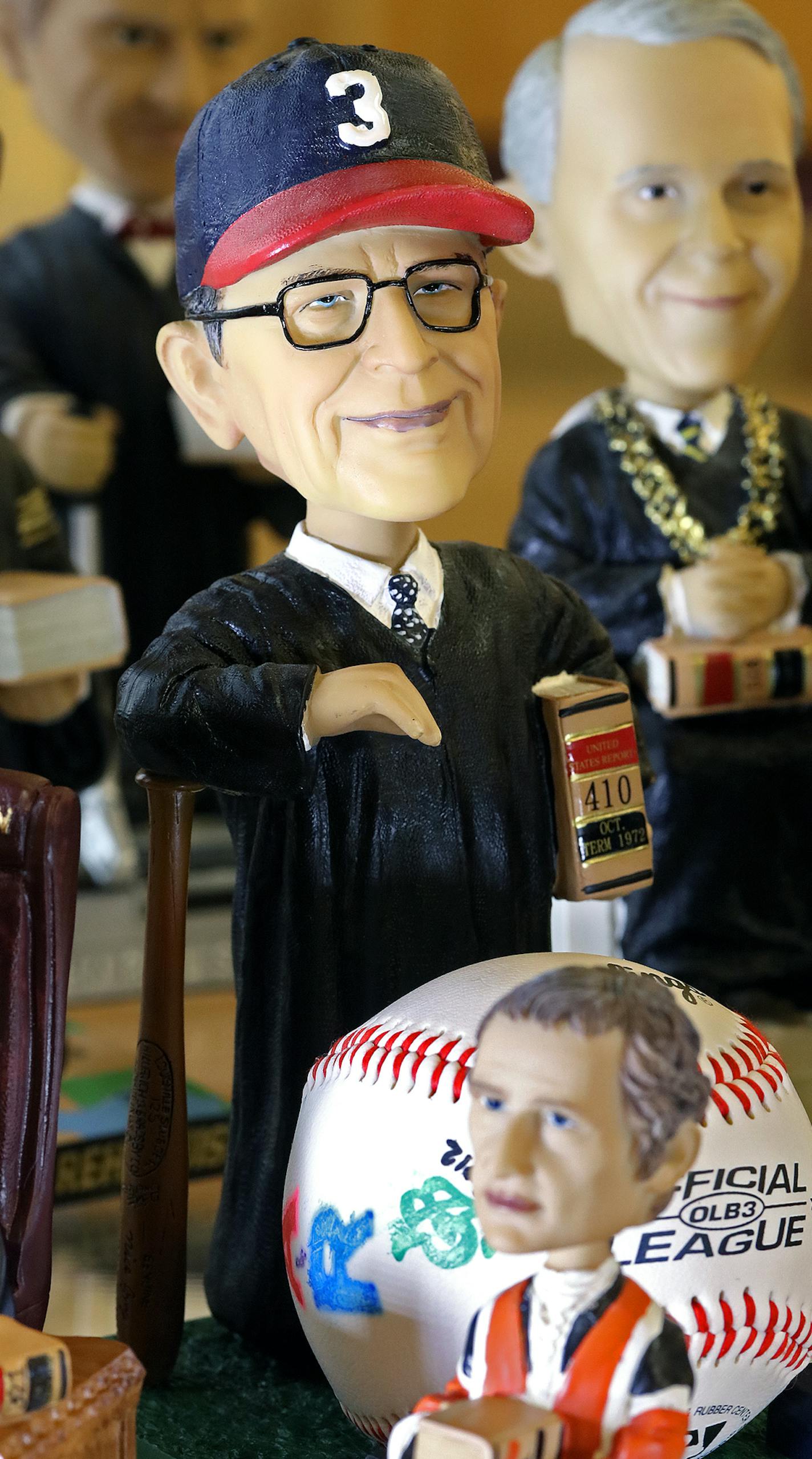 Justice Harry Blackmun's bobblehead wears a hat in Twins colors and leans on a bat.