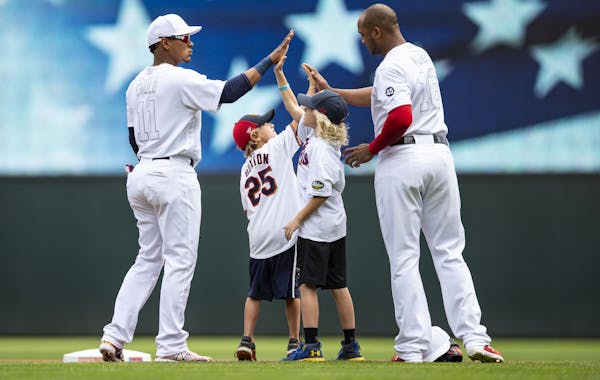 Minnesota Twins shortstop Jorge Polanco (11) and second baseman Jonathan Schoop (16) high fives young fans before the game.