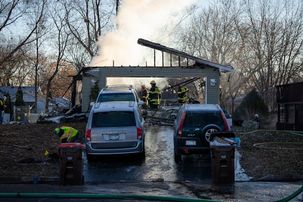 Fire crews work to put out a fire after a house explosion that killed at least two people and destroyed a home in South St. Paul, Minn. Thursday, Nov.