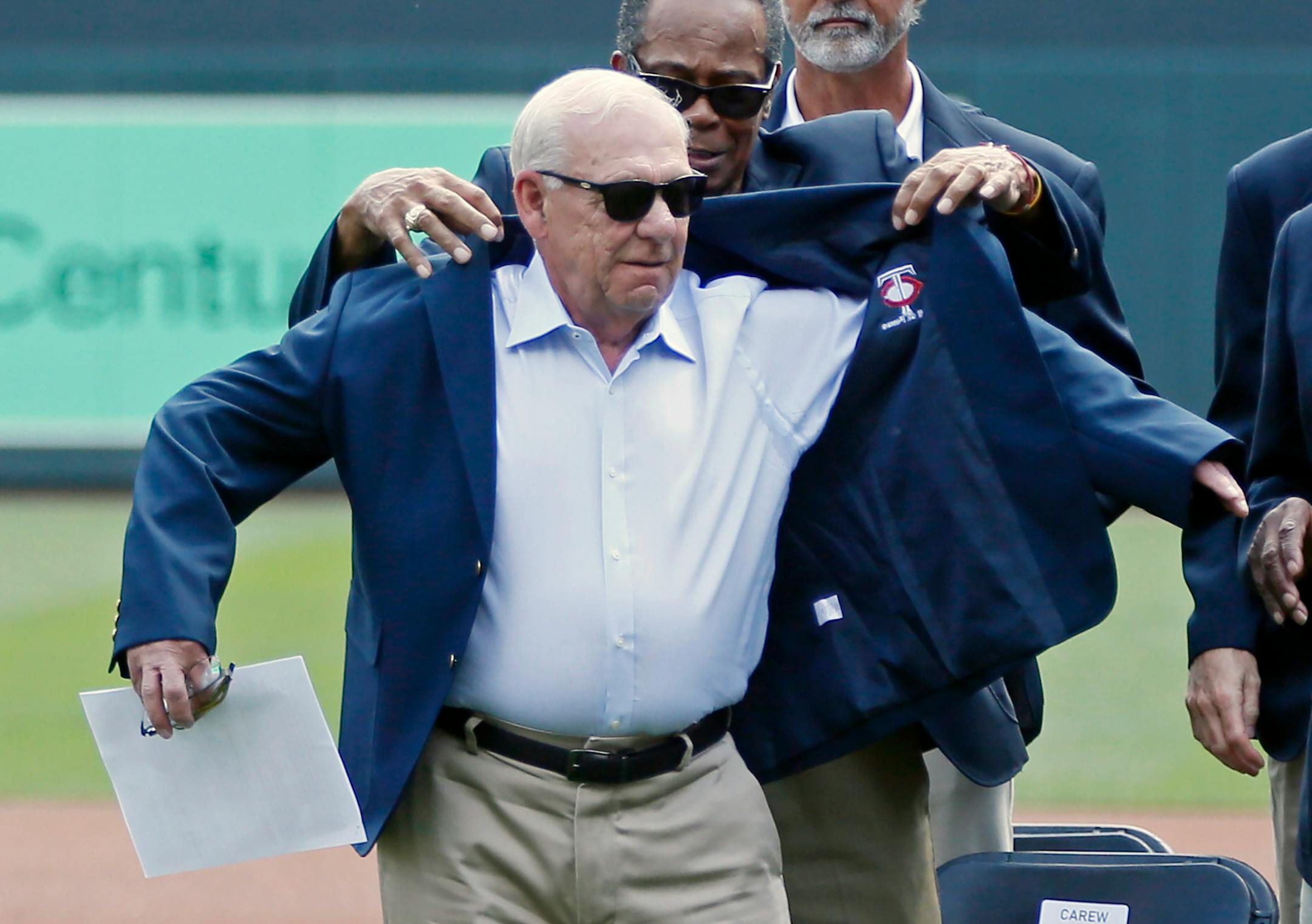 Minnesota Twins great Rod Carew helps with the jacket as Jerry Bell, left, former president of the Twins, was inducted into the Twins Hall of Fame prior to a baseball game against the Kansas City Royals Sunday, Aug. 4, 2019, in Minneapolis. (AP Photo/Jim Mone)