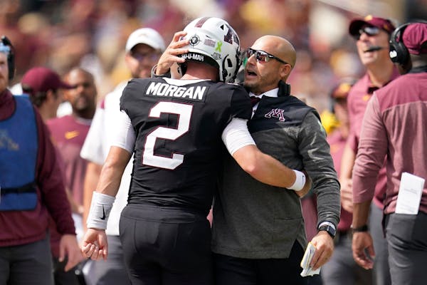 Minnesota quarterback Tanner Morgan, left, and head coach P. J. Fleck, right, share a hug during the Gophers' win over Western Illinois.