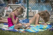 Adam Nafziger's children, Freya, 9, left, and Linus, 11, right, read their books as they waited for the pool to open from a break at the Richfield poo