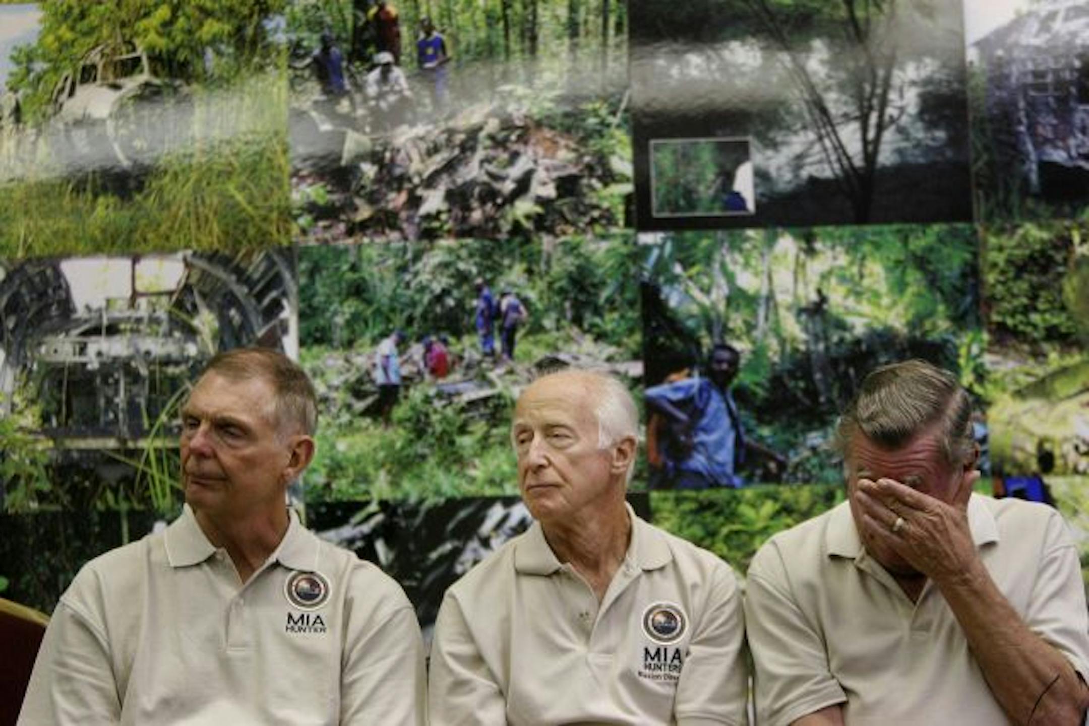 Dennis Thompson, left, of Lakeville, MN, Ralph Stillman, of Deephaven, MN, center, and John Syverson, of Park Rapids, MN listened as WWII veteran Richard L. Carroll talked about being shot while serving in the war. They were sitting in front of photos of what the MIA group calls "MIA graveyards."