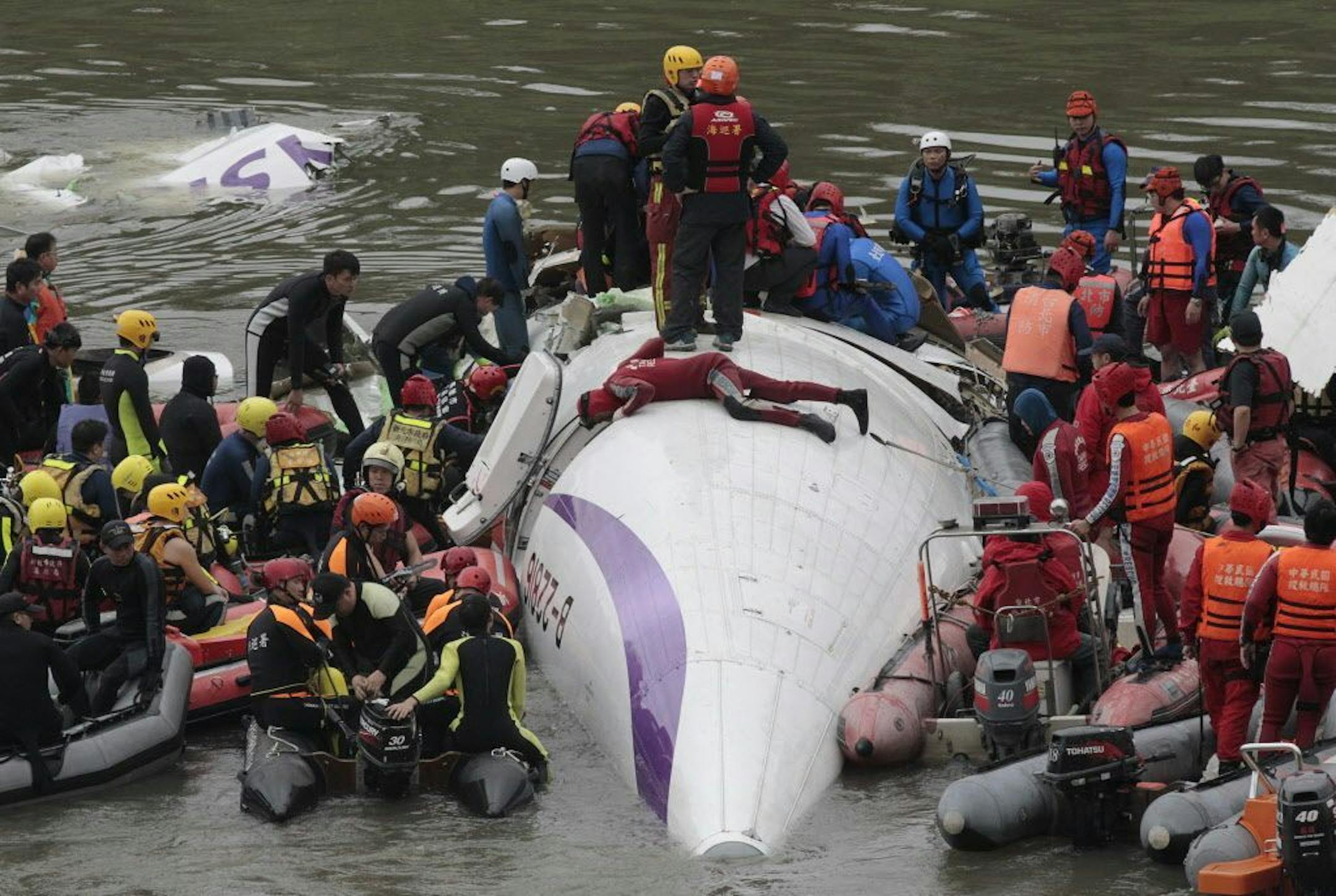 Emergency personnel try to extract passengers from a commercial plane after it crashed in Taipei, Taiwan, Wednesday, Feb. 4, 2015. The Taiwanese commercial flight with 58 people aboard clipped a bridge shortly after takeoff and crashed into a river in the island's capital on Wednesday morning.