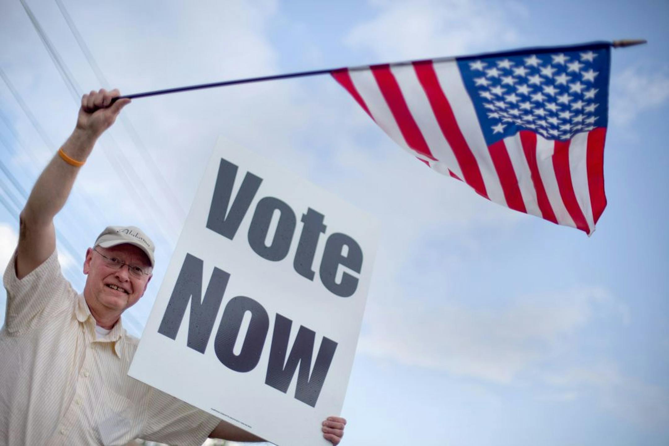 Danny Cooper, of Chilton County, Ala. waves to motorists outside a polling place, Tuesday, March 13, 2012, in Vestavia Hills, Ala. Alabama voters would be deciding Tuesday whether Mitt Romney has deep South appeal, if it's time for Newt Gingrich to go forward or go home, and whether Rick Santorum can trim the Republican field.