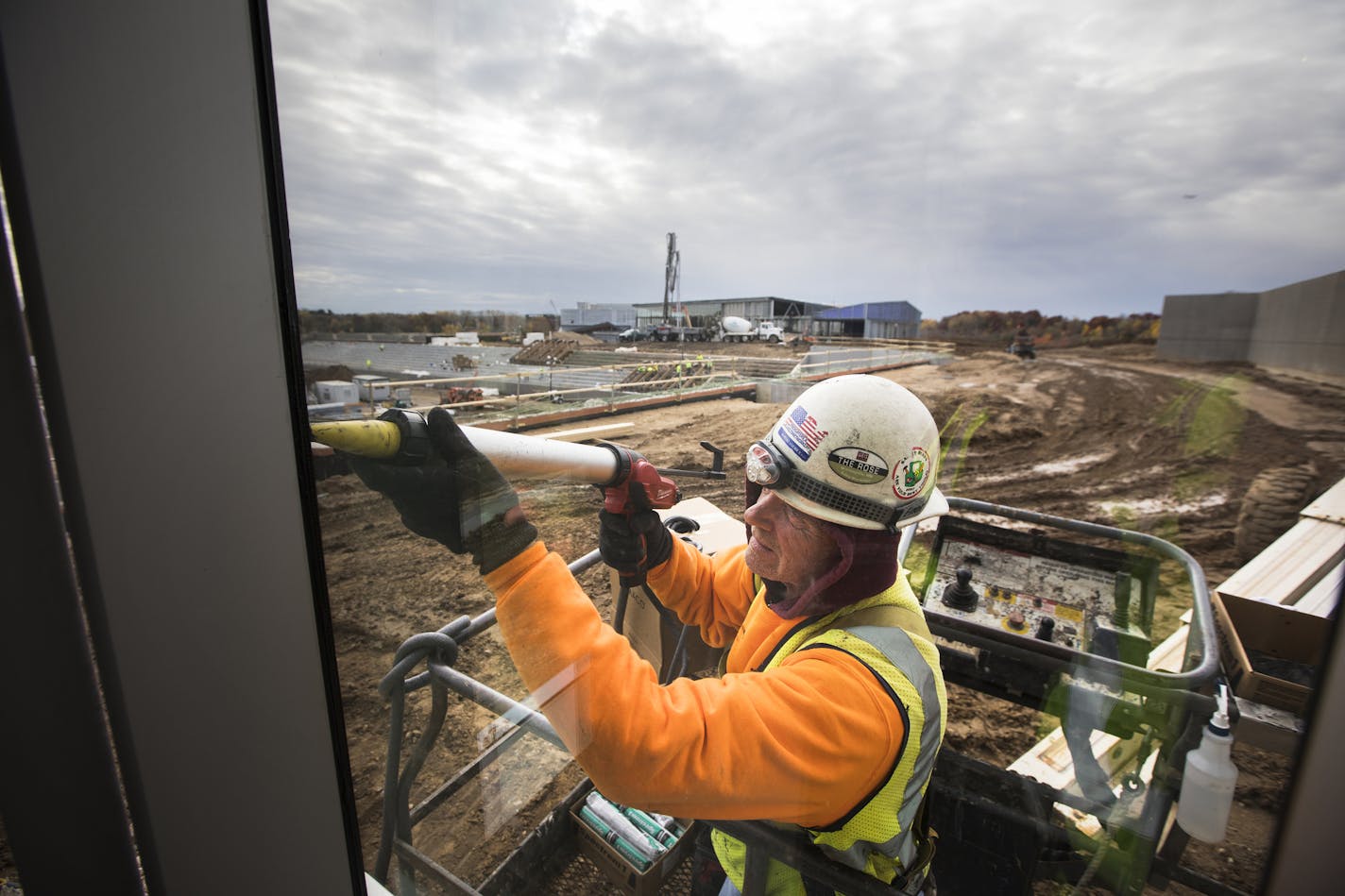 A construction worker finishes the caulking of the outside of the Vikings office building, which overlooks the stadium, seen behind him. ] LEILA NAVIDI &#xef; leila.navidi@startribune.com BACKGROUND INFORMATION: Media tour of the new Vikings facility the Twin Cities Orthopedics Performance Center in Eagan on Monday, October 23, 2017.