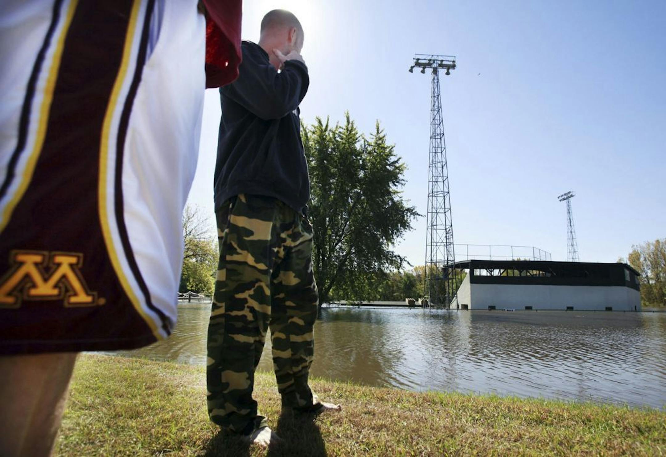 Flood waters that plagued much of southern Minnesota from recent torrential rains have moved closer to the Twin Cities and are expected to crest Saturday. In this photo:] Andrew Stier, left, and Bo Garner of Chaska look over flood waters from the swollen Minnesota River that swamped the Athletic Park ball field. Garner said he canoed in the outfield after spring flooding but that the water was higher now. Garner works at the nearby Demcon Landfill outside of Chaska and he said that it normally t