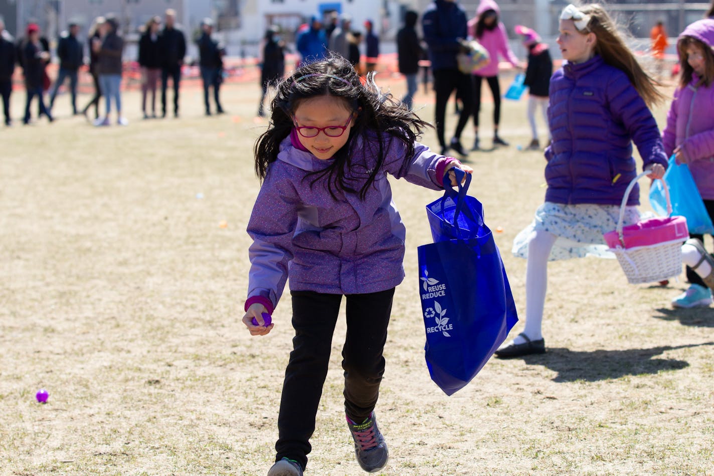 Child in purple coat hunts for Easter eggs at Renovation Church in Blaine.