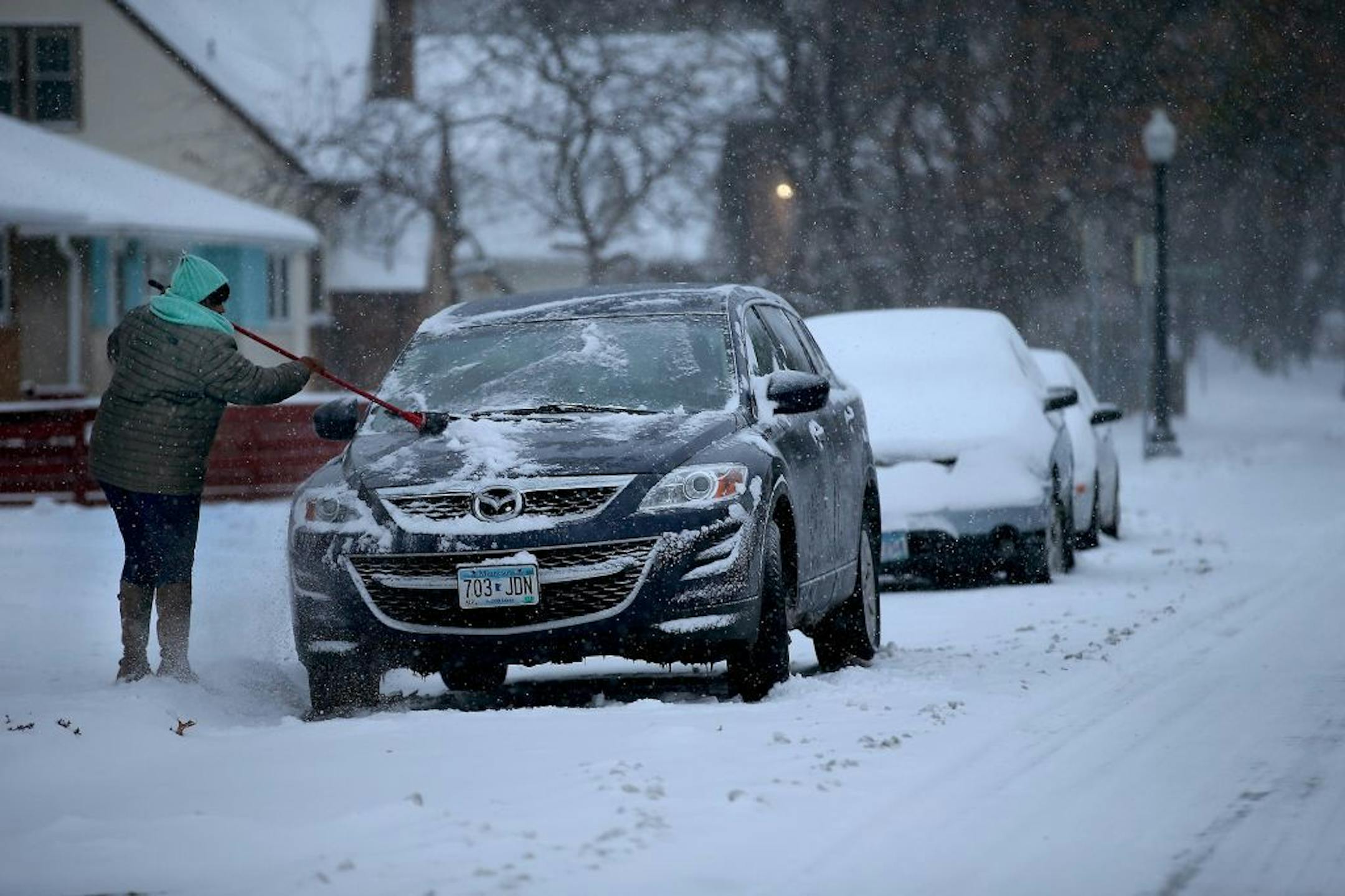 Stephanie Hollie cleared the snow off her car with a broom before she headed out to work, Tuesday, November 11, 2014 in Minneapolis, MN.