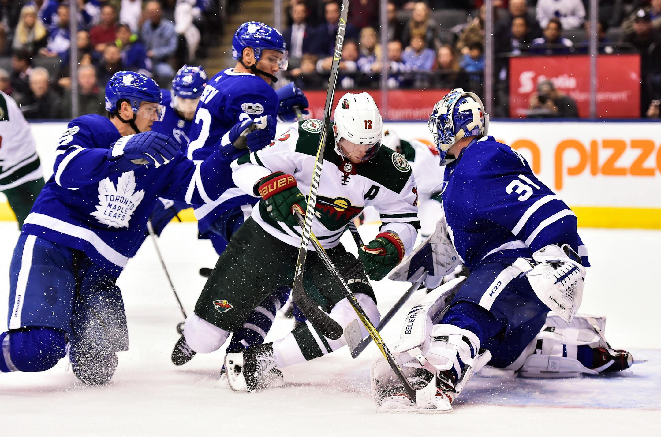 Toronto Maple Leafs defenseman Ron Hainsey, left, hits Minnesota Wild center Eric Staal (12) into goalie Frederik Andersen (31) during the third period of an NHL hockey game Wednesday, Nov. 8, 2017, in Toronto. (Frank Gunn/The Canadian Press via AP)