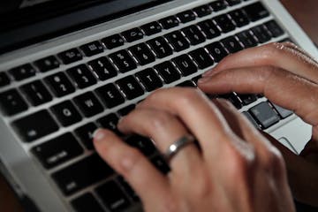 FILE- In this June 19, 2017, file photo, a person types on a laptop keyboard in North Andover, Mass. The availability of remote work has increased sig