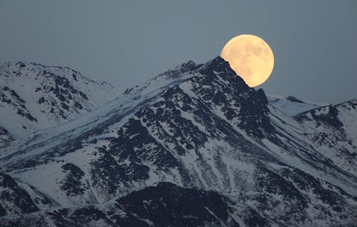 The moon rises above the Chugach Mountains in a view near Eagle River, Alaska on Tuesday, Jan. 18, 2011.
