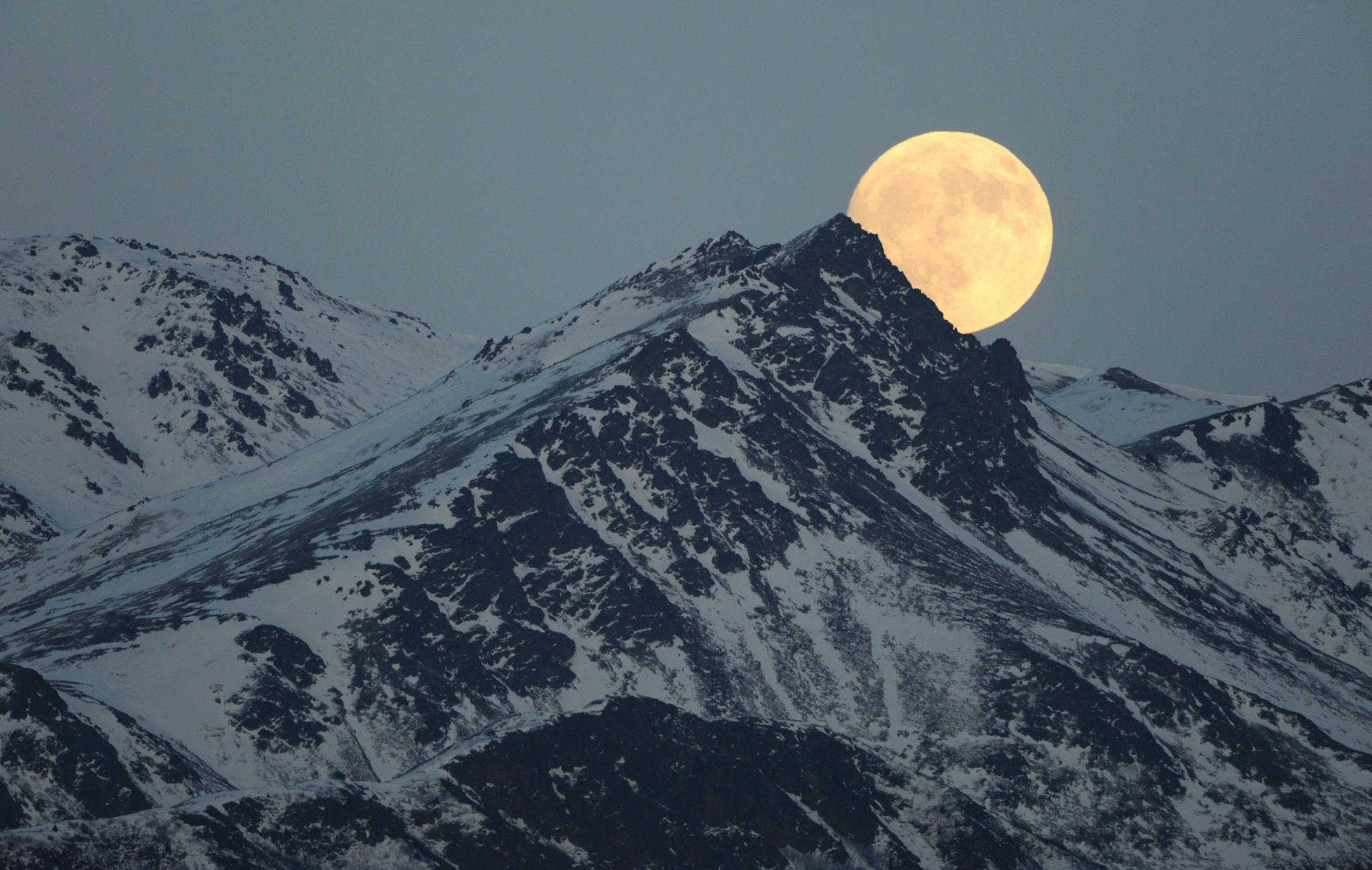 The moon rises above the Chugach Mountains in a view near Eagle River, Alaska on Tuesday, Jan. 18, 2011.
