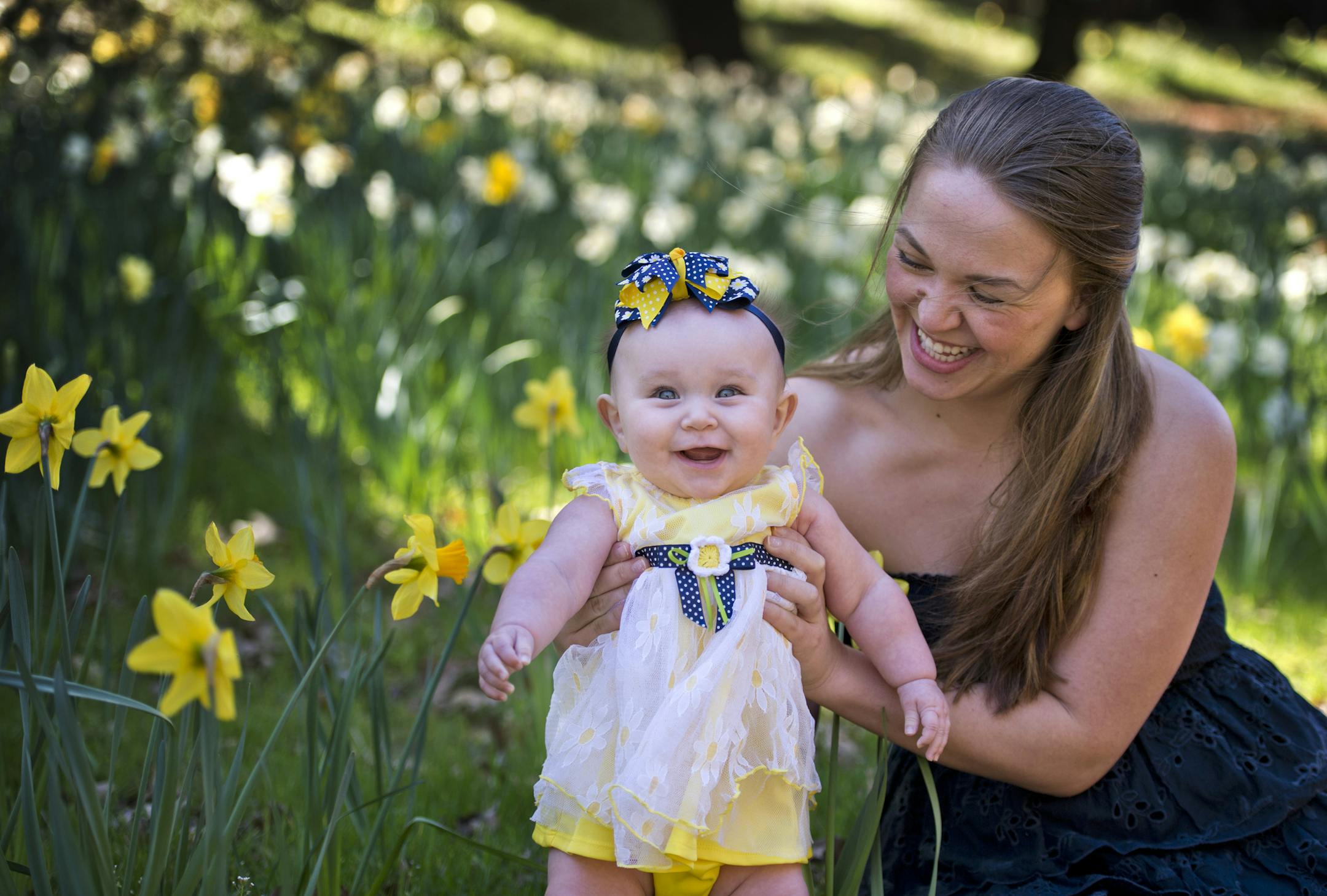 Two-year-old Autumn Perez, left, smiles as she is held by her mother Laura Reynolds, of Folsom, Calif., while they have their picture taken by father Joey Perez on McLaughlin's Daffodil Hill on Wednesday, March 19, 2014, in Amador County, Calif. The family was taking advantage of the warm weather and the newly opened blossoms for a family photo. (AP Photo/The Sacramento Bee, Hector Amezcua) MAGS OUT; LOCAL TV OUT (KCRA3, KXTV10, KOVR13, KUVS19, KMAZ31, KTXL40); MANDATORY CREDIT.