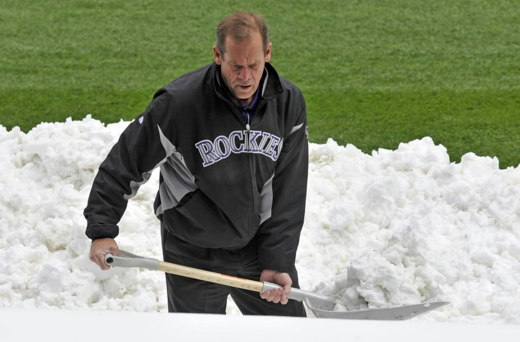 Colorado Rockies owner Dick Monfort shovels snow from the field before the start of a scheduled baseball double-header between the New York Mets and the Colorado Rockies on Tuesday, April 16, 2013, in Denver.