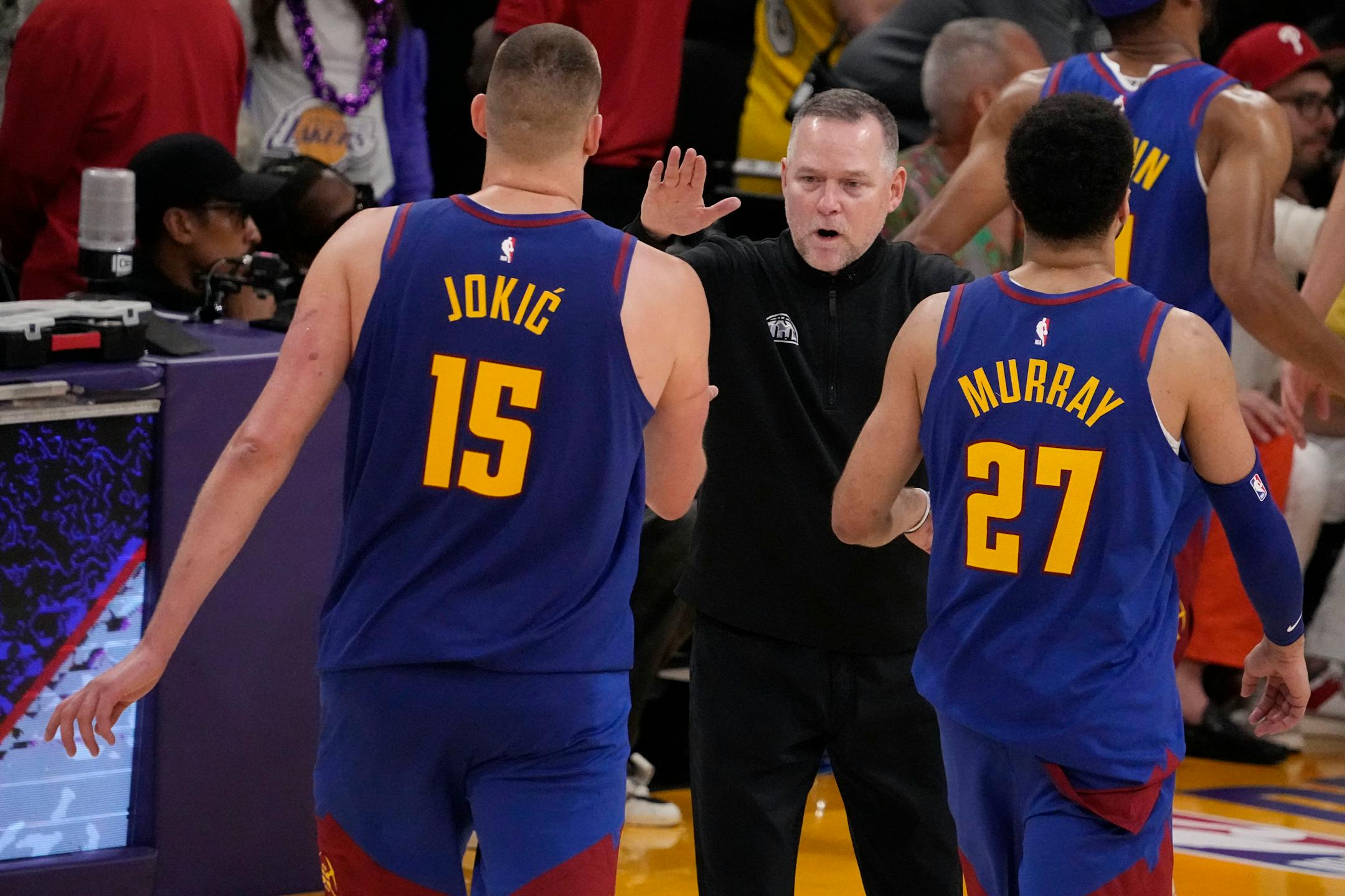 Denver Nuggets head coach Michael Malone, center, shakes hands with Denver Nuggets center Nikola Jokic (15) and guard Jamal Murray (27) in the second half of Game 3 of the NBA basketball Western Conference Final series against the Los Angeles Lakers Saturday, May 20, 2023, in Los Angeles. (AP Photo/Mark J. Terrill)