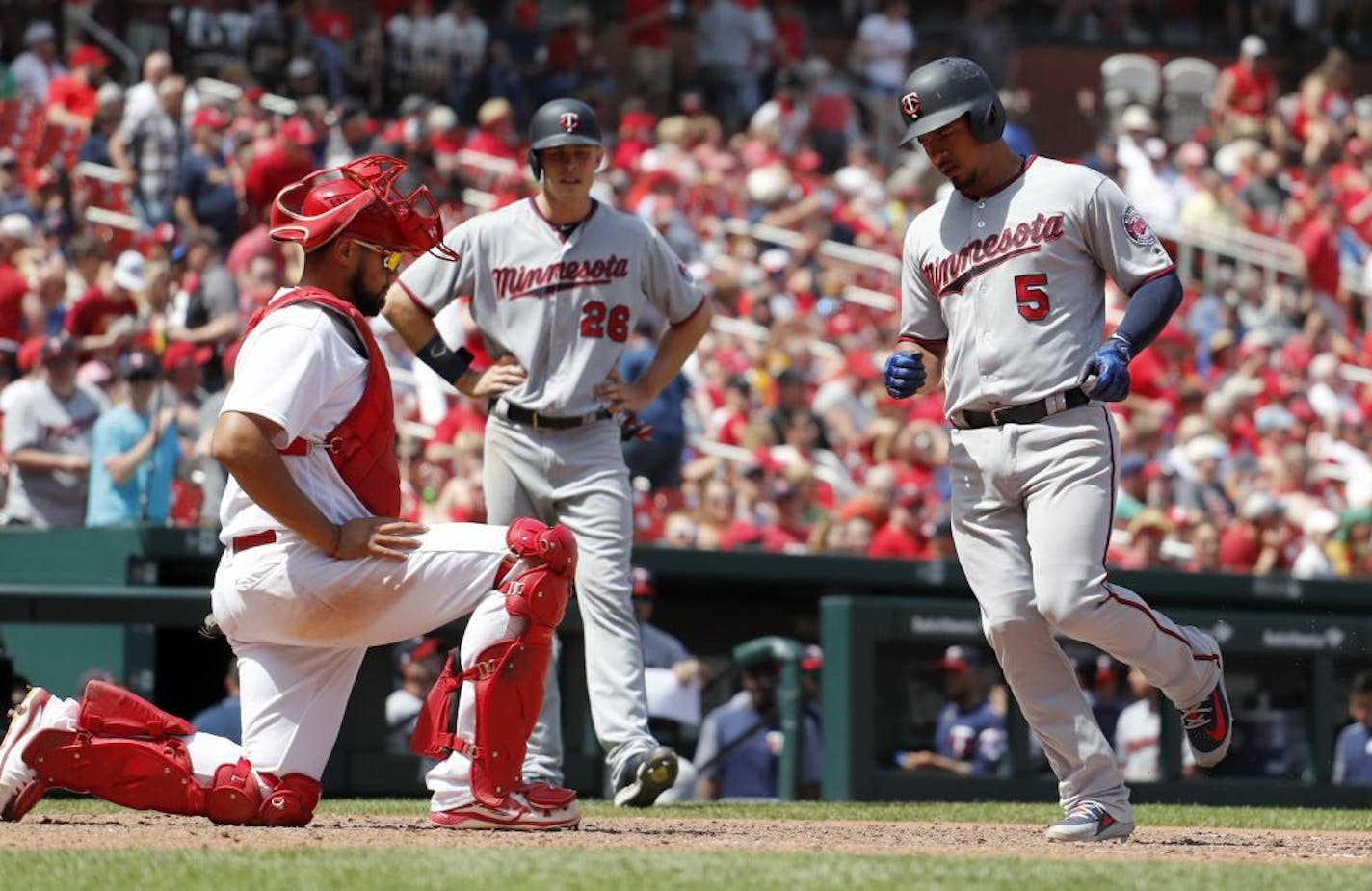 Minnesota Twins' Eduardo Escobar (5) arrives home after hitting a two-run home run during the seventh inning of a baseball game as teammate Max Kepler (26) and St. Louis Cardinals catcher Francisco Pena, left, watch Tuesday, May 8, 2018, in St. Louis. The Twins won 7-1.