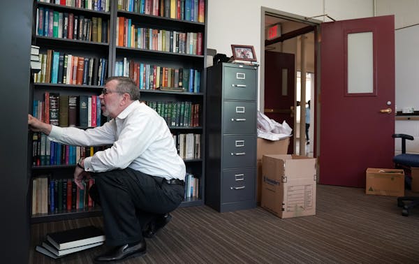 Outgoing president Eric Kaler organized his bookshelf as he unpacked boxes in his new office at Amundson Hall. ] ANTHONY SOUFFLE &#x2022; anthony.souf