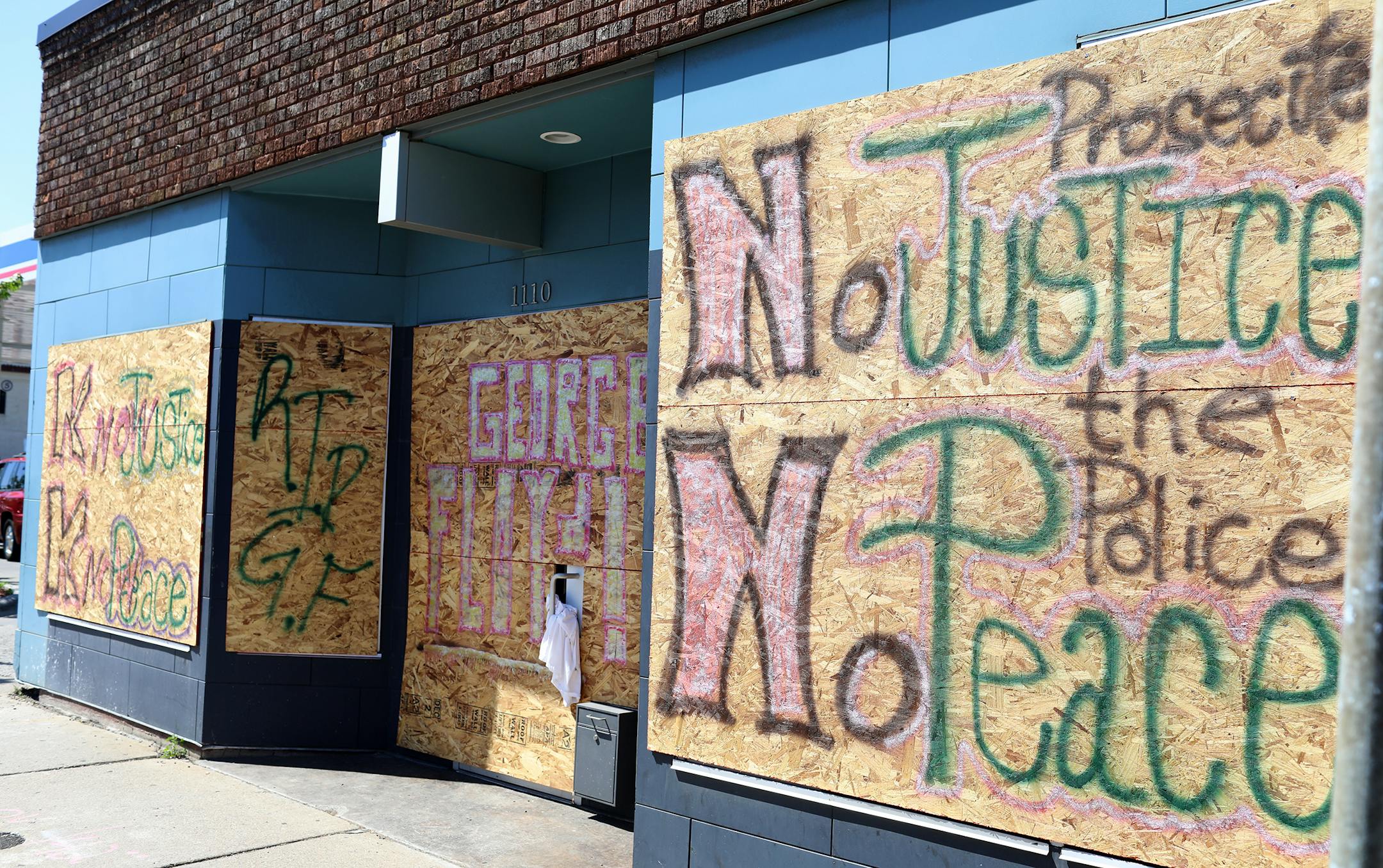 Protestor's rallying cry "No Justice No Peace" and George Floyd's name mark the boarded-up windows at 1110 W. Broadway Ave. in North Minneapolis.