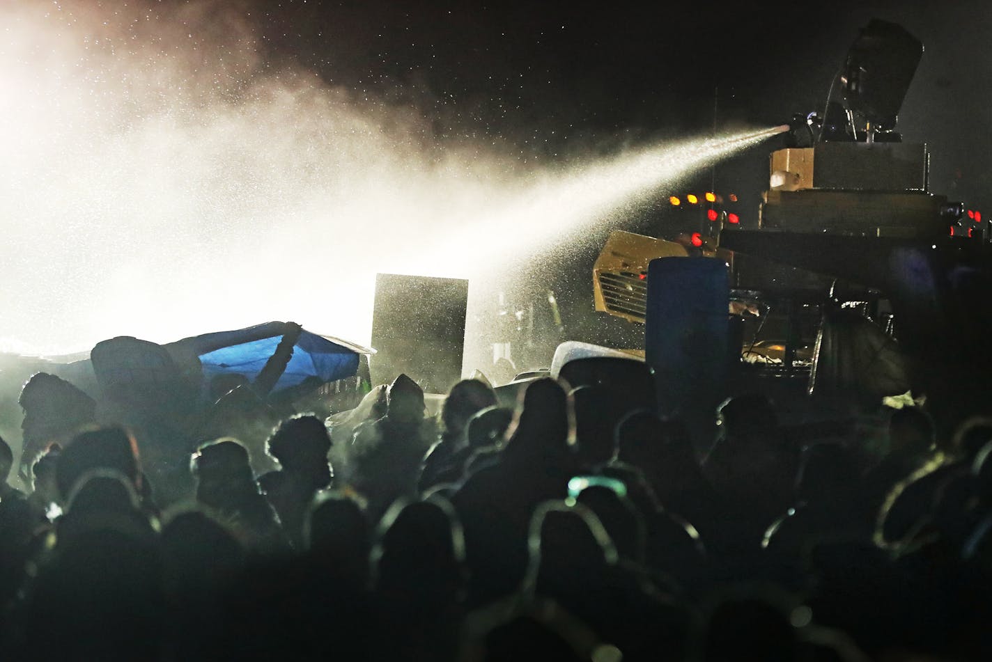 Law enforcement officers use a water cannon against protesters at a bridge leading to the DAPL Pipeline construction near the Standing Rock Reservation in North Dakota.