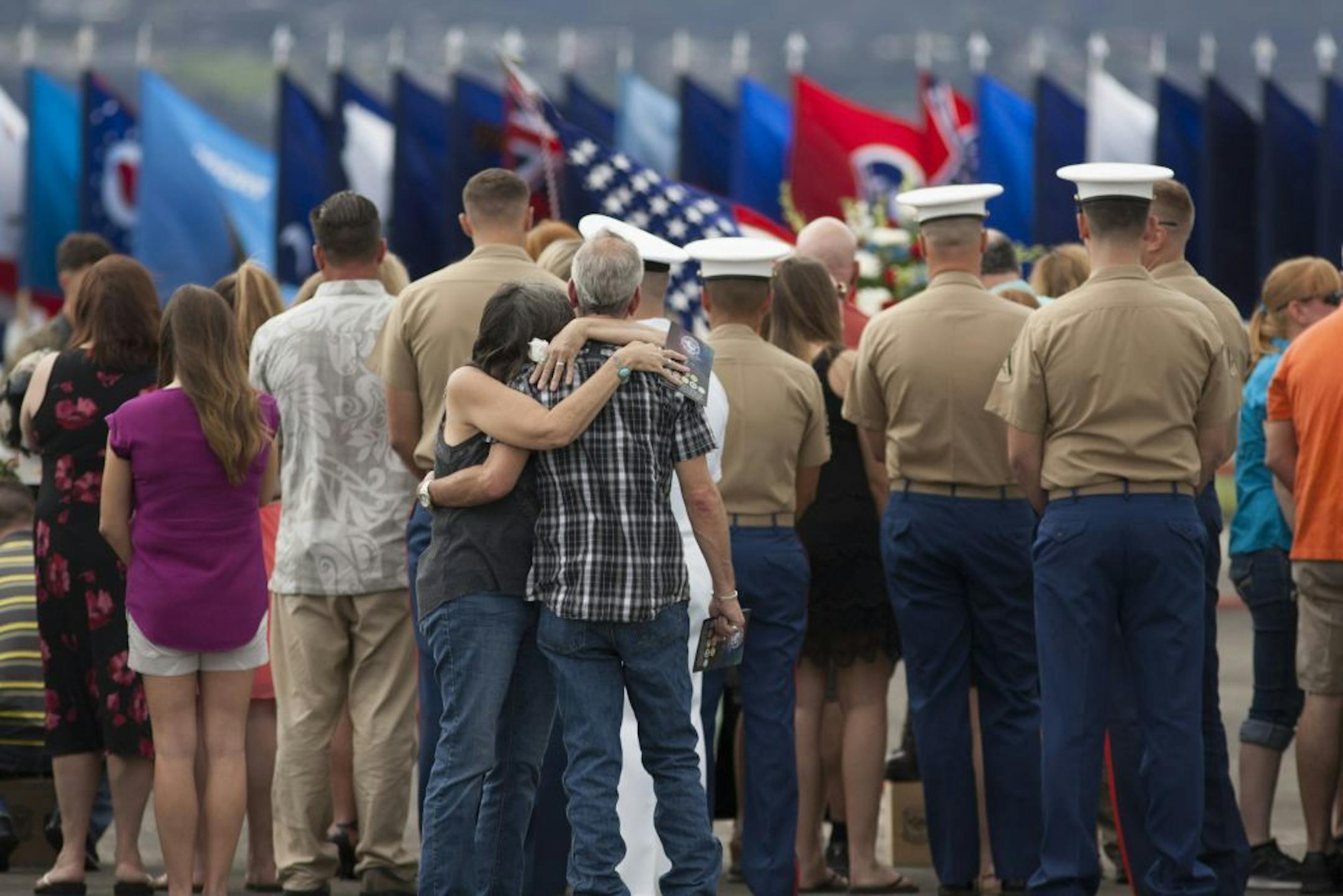 Unidentified family members embrace around a memorial for the 12 Marines who died when their helicopters crashed off the North Shore of Oahu, Hawaii, Friday Jan. 22, 2016, at Marine Corps Base Hawaii. Servicemen draped flight gear on 12 white crosses Friday to commemorate the Marines who died when two helicopters crashed off the coast of Hawaii during a nighttime training mission. Military members and families gathered for the memorial service at Marine Corps Base Hawaii in Kaneohe after the sta