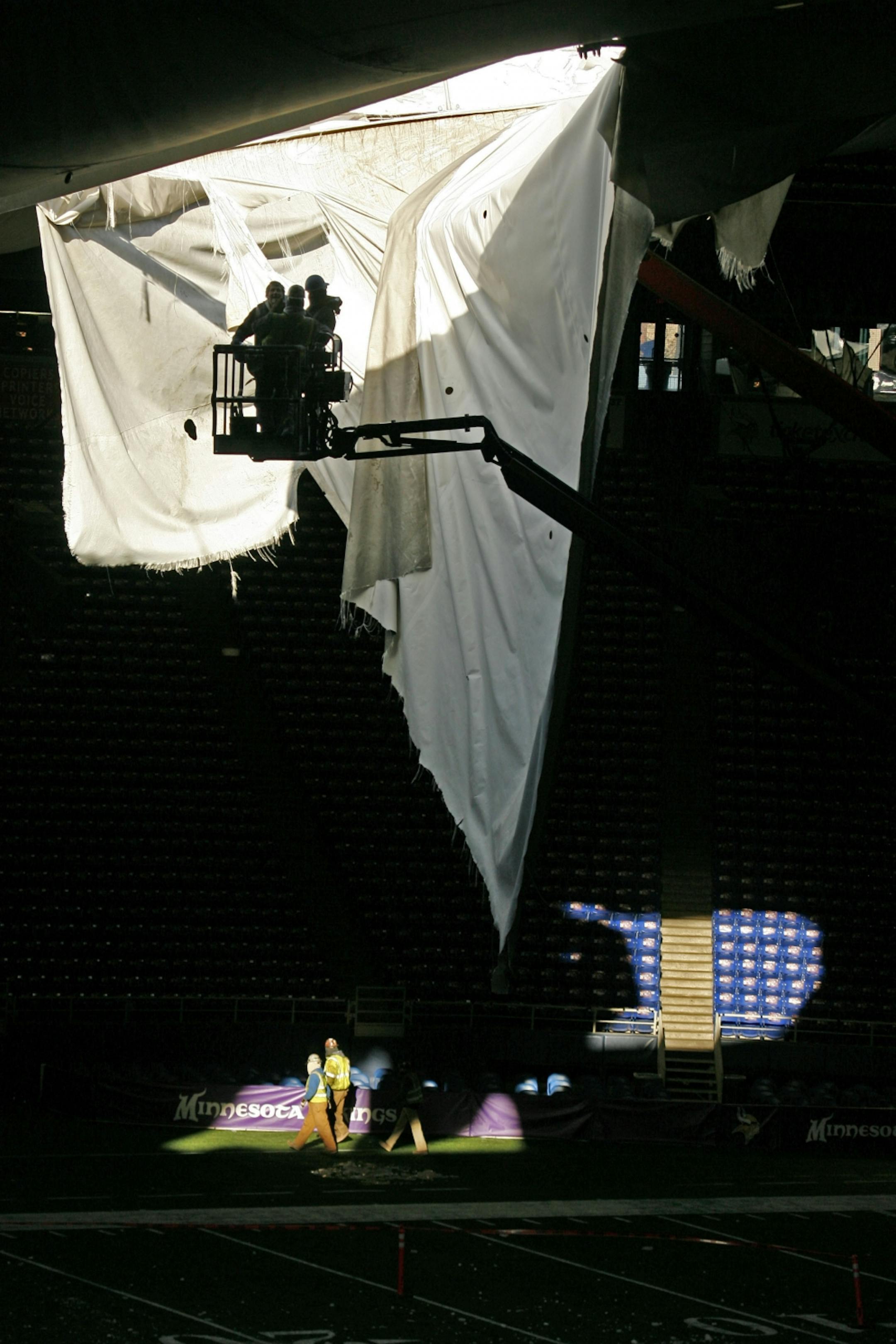 Workers inspect the roof and cut down sections.