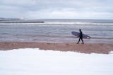 A surfer walked along the snow-covered shore of Lake Superior in Duluth on a January day.