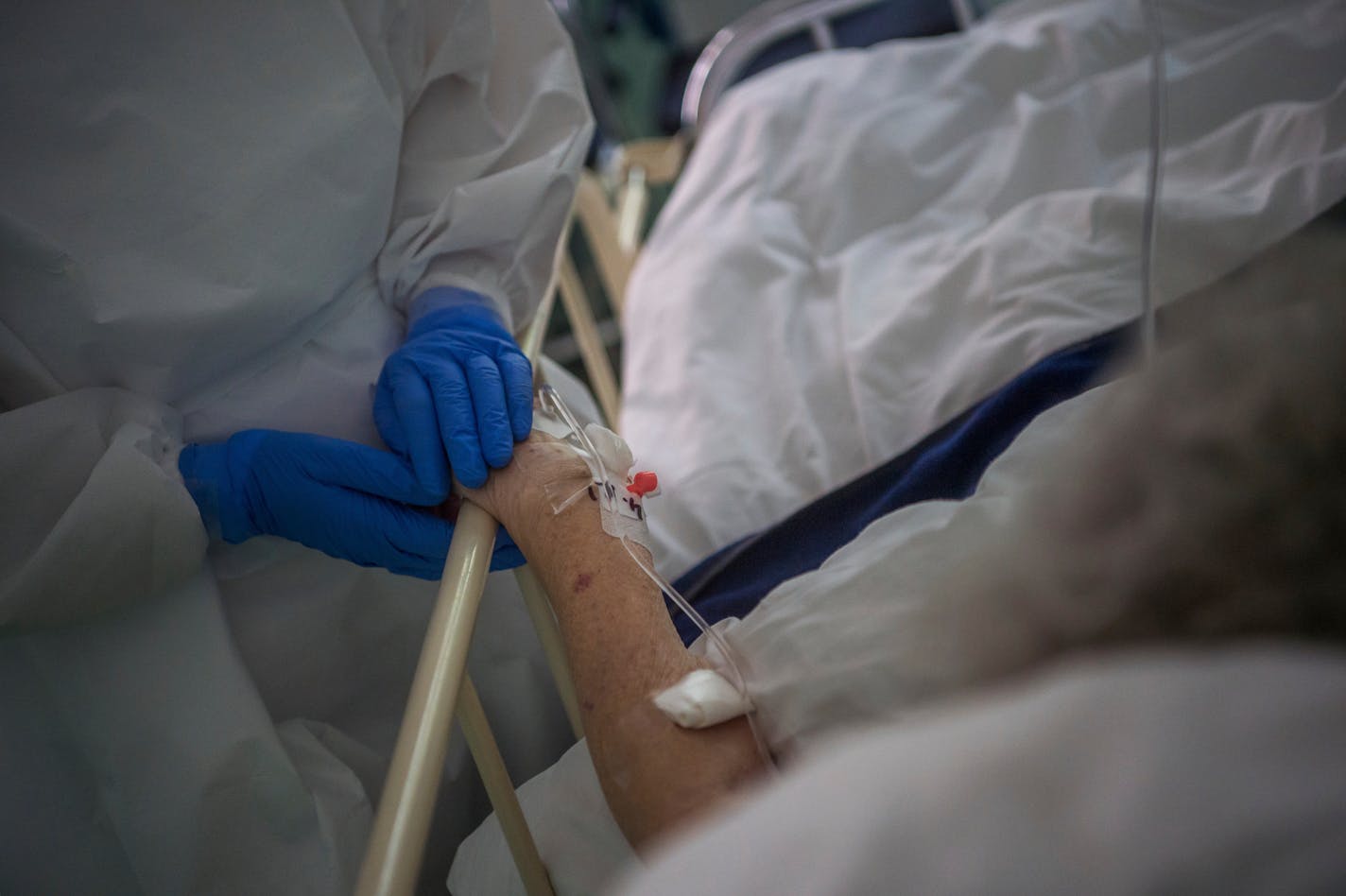 A nurse wearing protective gear caresses a patient's hand in the Covid Orthopedic-Traumatology Department of the St. Janos hospital in Budapest, Hungary.