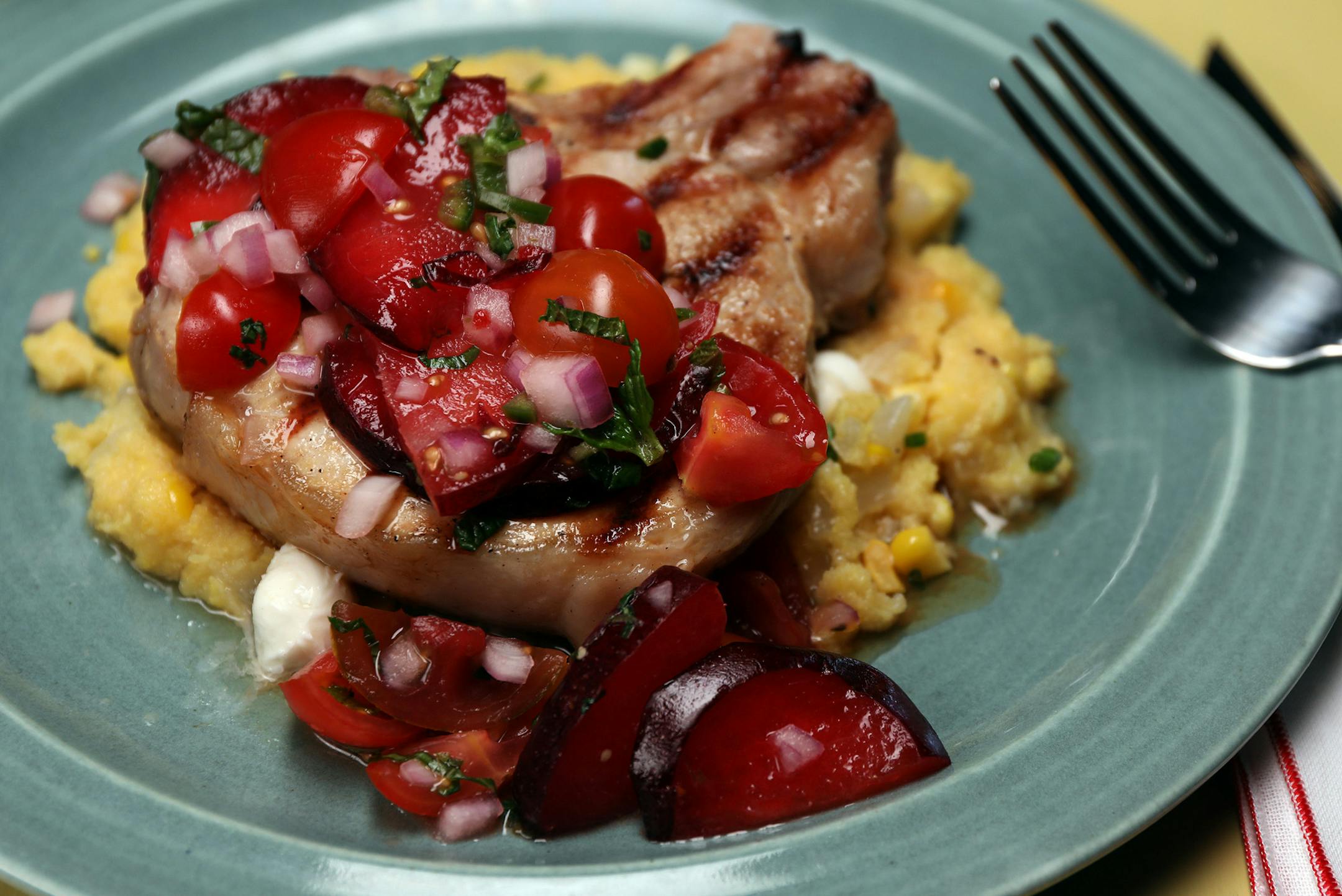 Whiskey-brined pork chops topped with tomato-plum relish served atop sweet corn and chive polenta. (Terrence Antonio James/Chicago Tribune/TNS) ORG XMIT: 1237649