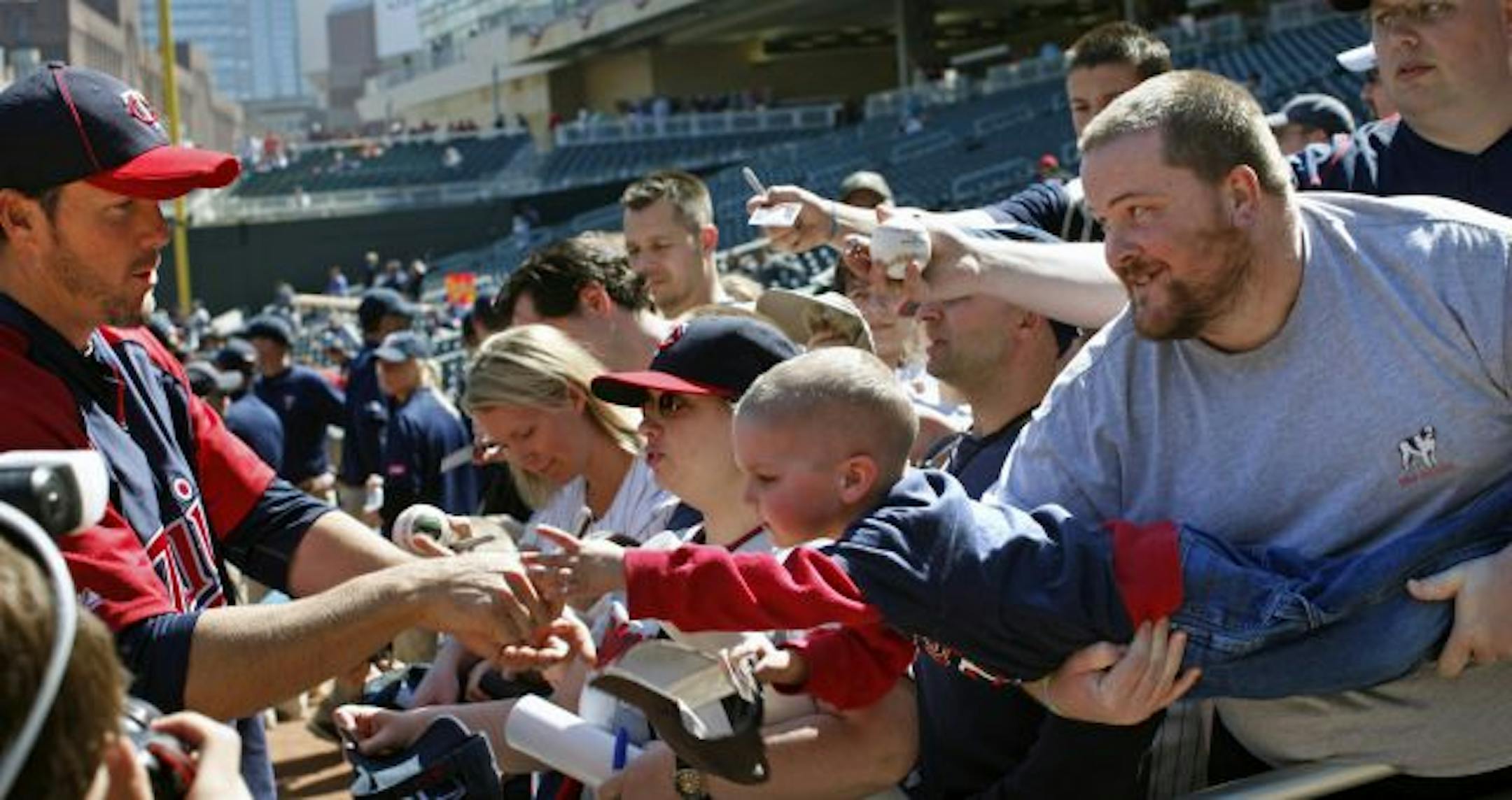 TWINS -vs- OAKLAND OPENING DAY - ] 5-year-old Rowen McKnight got an unexpected boost by Jay Black of Medilia in an attempt to get an autograph from Twins pitcher Joe Nathan before the home opener Friday afternoon.