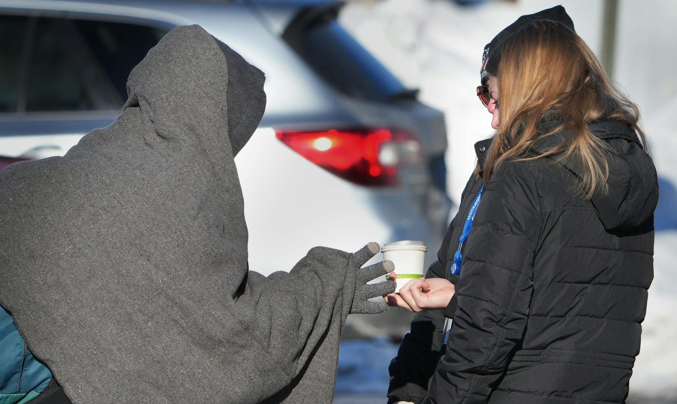 Mim Buckland of the Hennepin County Streets 2 Housing program hands a cup of coffee to a resident of a homeless encampment off of the 3000 block of Snelling Avenue.