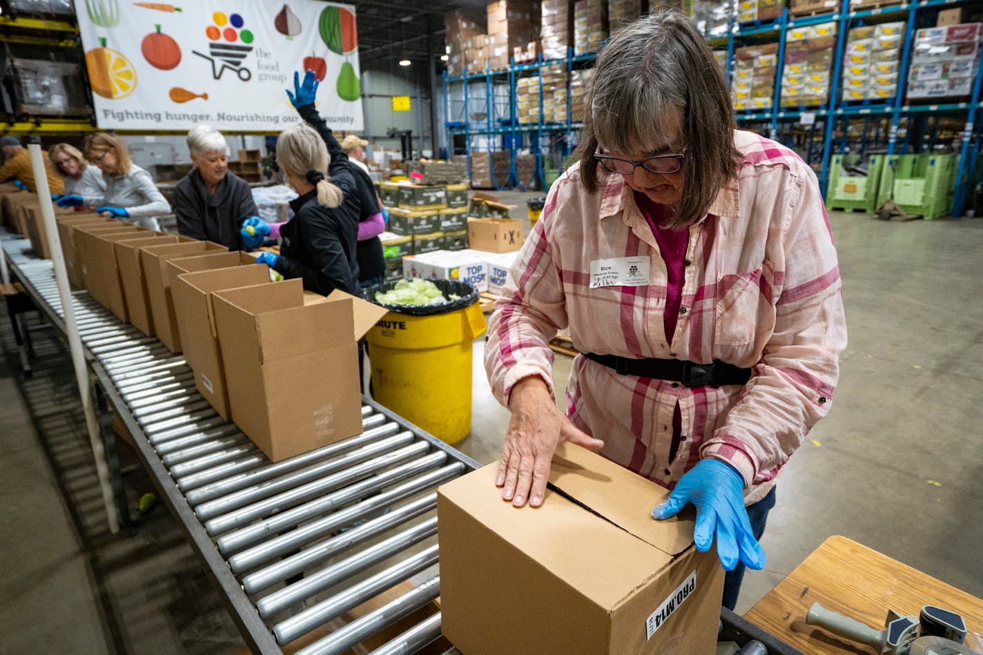 Kathy Kosik, a volunteer with the Food Group, helps package produce boxes during the food bank's "Pack to the Max" event on the 15th annual Give to the Max Day at the Food Group in New Hope, Minn. on Thursday, Nov. 16, 2023. This day is the biggest one-day fundraiser for thousands of Minnesota schools and nonprofits and the Food Group is hoping to raise at least $100,000 by the end of the day. They are also distributing the boxes to food shelves and other affordable grocery programs in Minnesota to get healthy food in the hands of people in need. ] Angelina Katsanis • angelina.katsanis@startribune.com