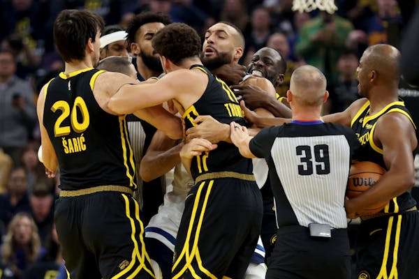 Golden State Warriors’ Klay Thompson, front, and Draymond Green, back, get into an altercation with Timberwolves center Rudy Gobert early in the fir