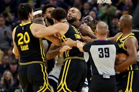 Golden State Warriors’ Klay Thompson, front, and Draymond Green, back, get into an altercation with Timberwolves center Rudy Gobert early in the fir