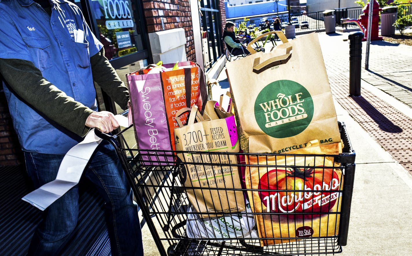 FILE &#xf3; A Whole Foods employee pushes a laden cart out of the store, in New York, Oct. 30, 2015. Amazon&#xed;s $13.4 billion purchase of Whole Foods is a shot across the bow of the grocery-store industry, and shares of Walmart, Target, Kroger and Costco all tumbled in response to the announcement on June 16, 2017. (Dolly Faibyshev/The New York Times)