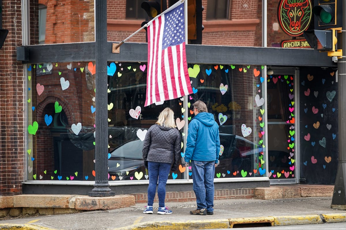 Restaurants remain closed in Hudson, Wisconsin where the Governor just postponed the state's in-person election. Here people read inscriptions on hand