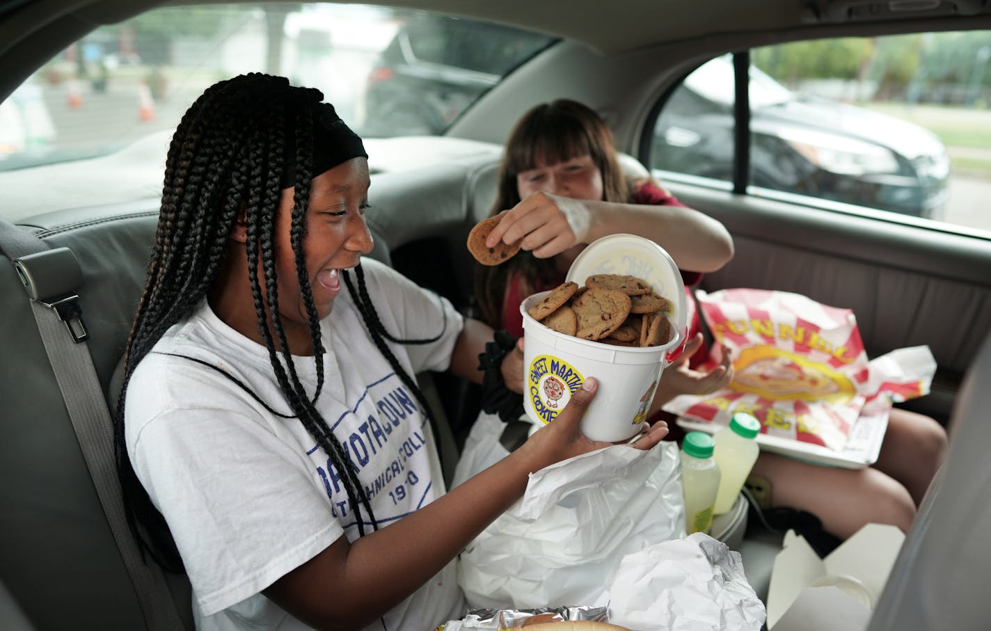 Nevaeh McCave, 12 and Laila Morneau were all smiles after getting a bucket of Sweet Martha Cookies on their final food stop Thursday morning at the fairgrounds. The Minnesota State Fair Food Parade got underway Thursday morning with the three weekend event serving up favorite fair food to drive up cars at various vendors. Here, brian.peterson@startribune.com St. Paul, MN Thursday, August 20, 2020