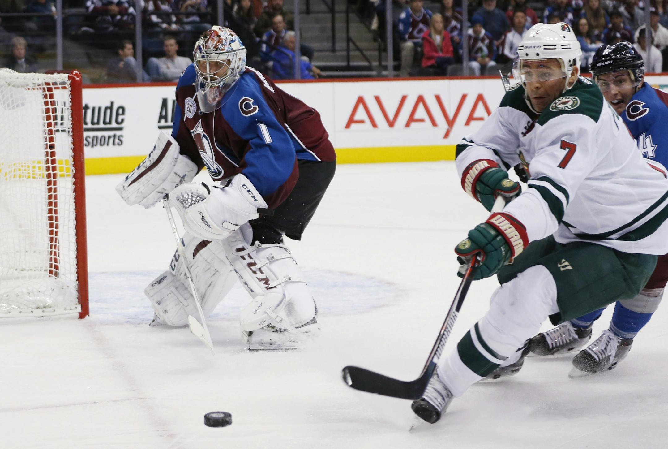Minnesota Wild left wing Chris Porter, front right, reaches for the puck as it is cleared by Colorado Avalanche goalie Semyon Varlamov, left, of Russia, while Avalanche defenseman Tyson Barrie, back right, covers in the second period of an NHL hockey game Monday, Dec. 7, 2015, in Denver.