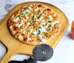 A homemade pizza is topped with Buffalo chicken, green onions and blue cheese dressing.