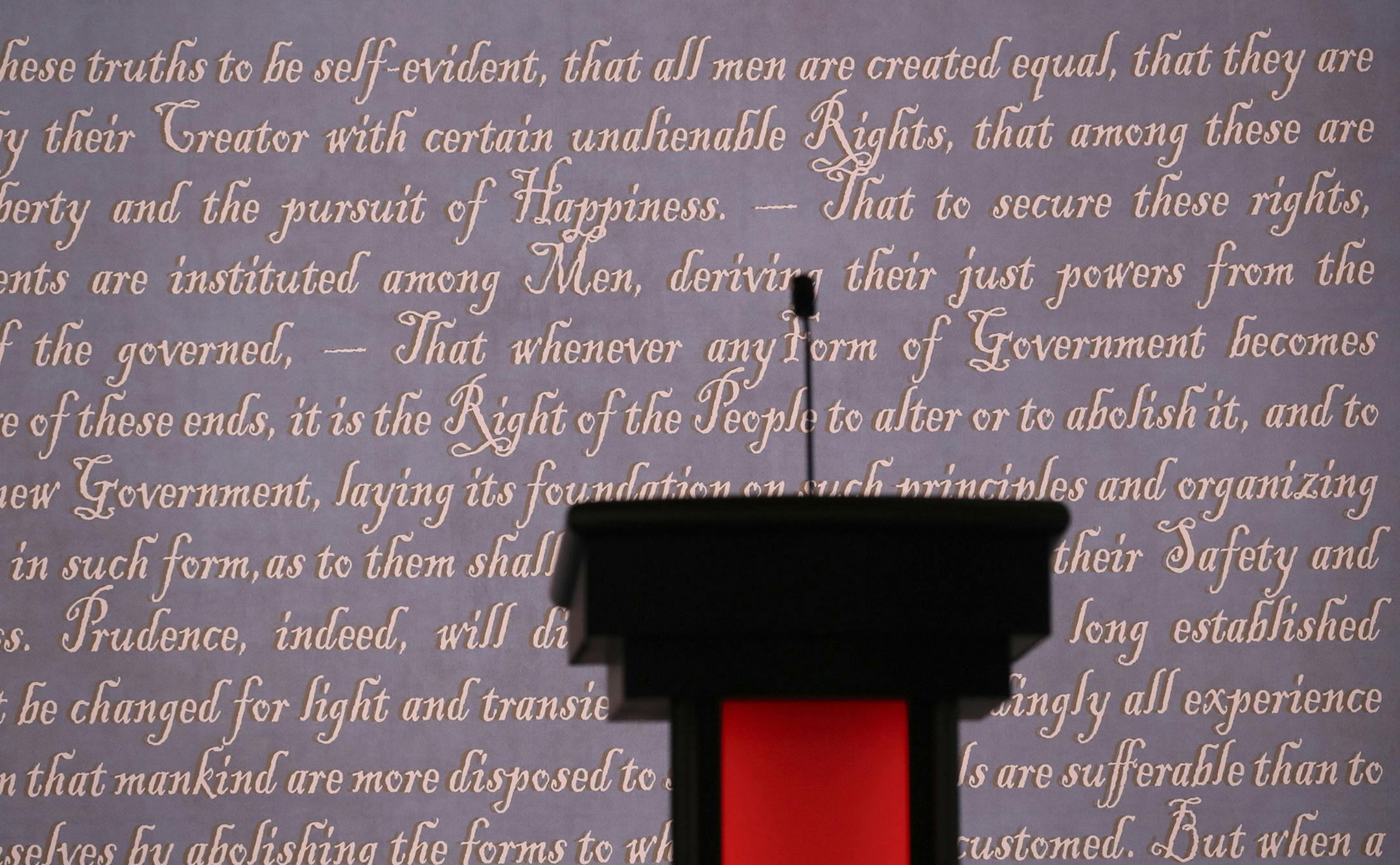 A podium in front of a video graphic of script from the Declaration of Independence at the venue for tonight's first debate between the presidential nominees Hillary Clinton and Donald Trump, at Hofstra University in Hempstead, N.Y., Sept. 26, 2016. With a race that once seemed to be tipping in Clinton’s favor growing more competitive as early voting begins, the debate is far more than a made-for-TV moment. (Damon Winter/The New York Times) ORG XMIT: MIN2016092711023006