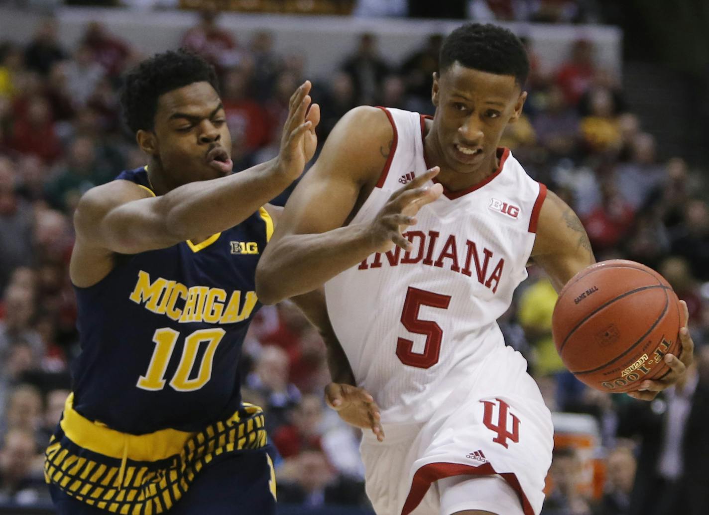 Indiana's Troy Williams (5) drives between Michigan's Derrick Walton Jr. (10) and Muhammad-Ali Abdur-Rahkman (12) in the first half of an NCAA college basketball game in the quarterfinals at the Big Ten Conference tournament, Friday, March 11, 2016, in Indianapolis. (AP Photo/Kiichiro Sato)