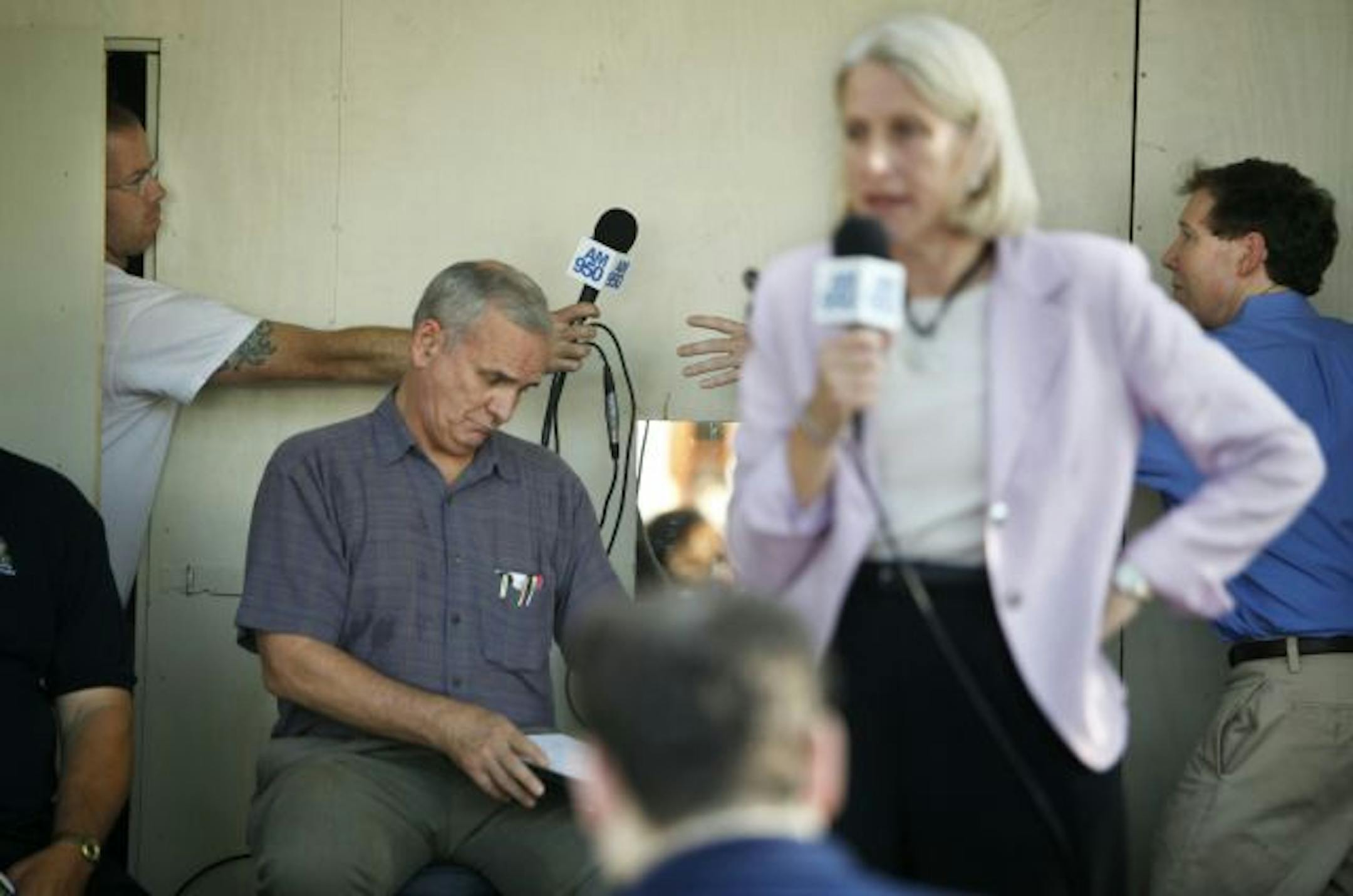 At a DFL gubernatorial candidates debate at the State Fair on Tuesday, sound engineer Justin Winick, left, passed a working microphone to host Mike McIntee, while former U.S. Sen. Mark Dayton prepared his notes and Ramsey County Attorney Susan Gaertner tested the malfunctioning microphone.