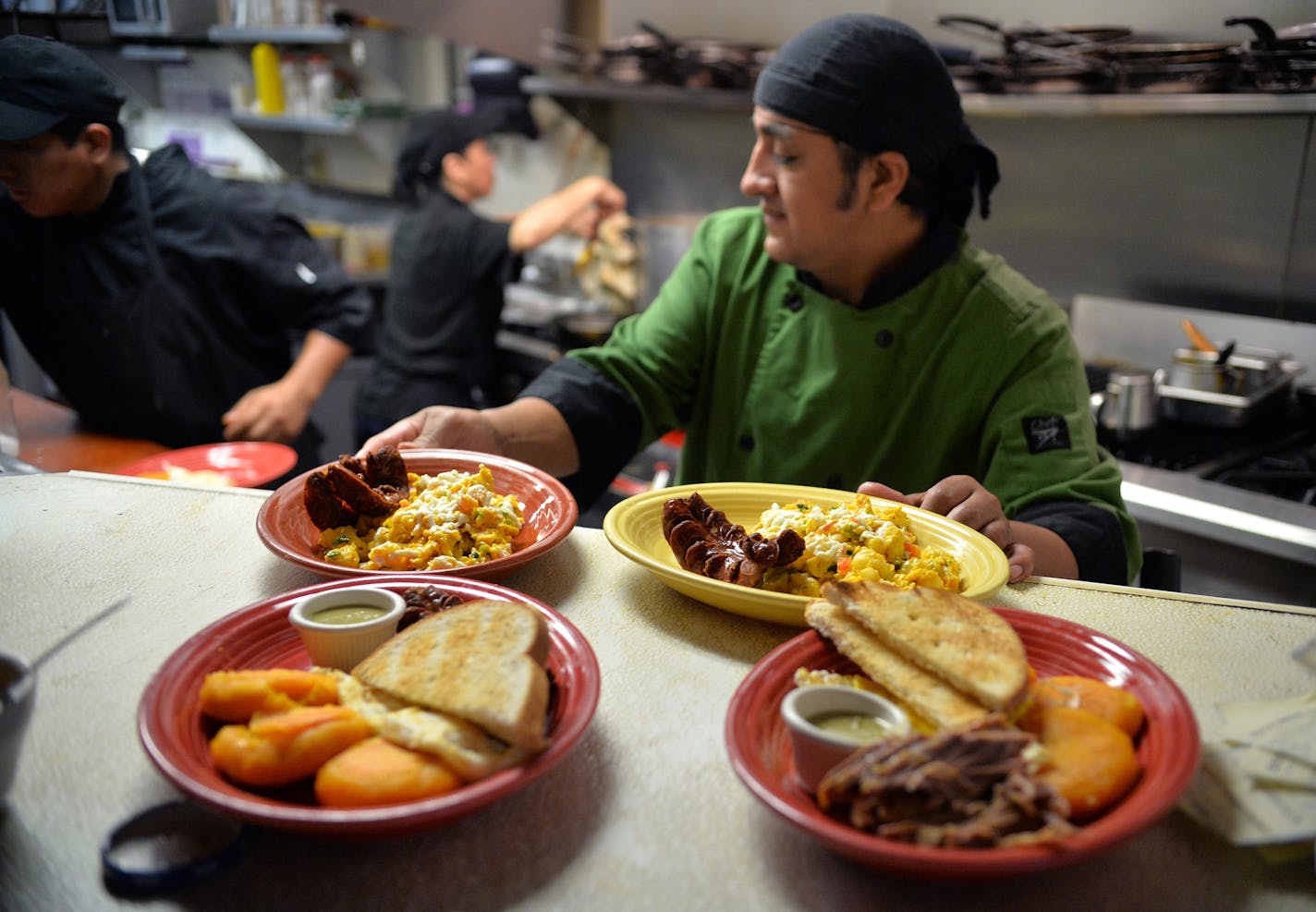 Owner and chef, Marcos Pinguil, sets prepared brunch dishes the counter before being delivered the hungry guests.